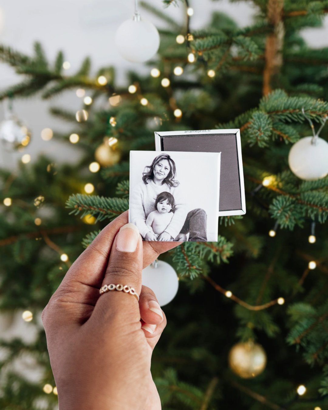 photo d'un magnet photo carré personnalisé de 5 cm devant un sapin de noël